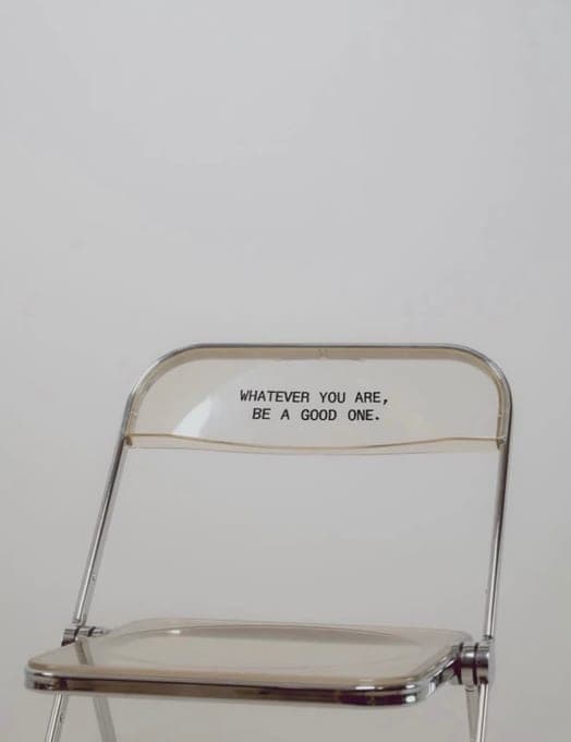 Chaise pliante transparente devant un mur blanc