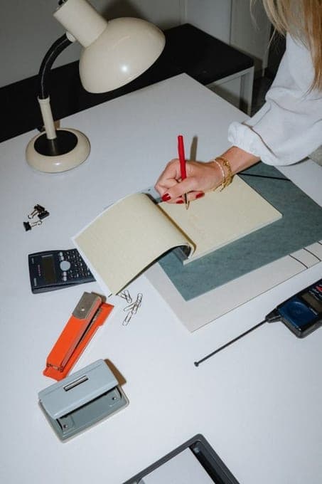 Bureau vu de haut : carnet ouvert, lampe articulée et stylos